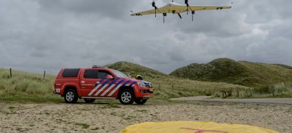 Brandweerwagen op het strand terwijl een vliegtuigdrone landt