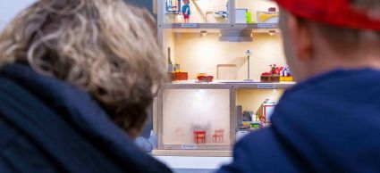 Bezoekers kijken naar houten huisje waarin fictief brand ontstaat