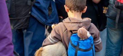 jongetje met rugzak in groep vluchtelingen