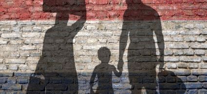 nederlandse vlag op de muur waarop schaduw van gezin te zien is met koffers en tassen
