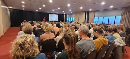 Zaal vol mensen die luisteren naar de spreker