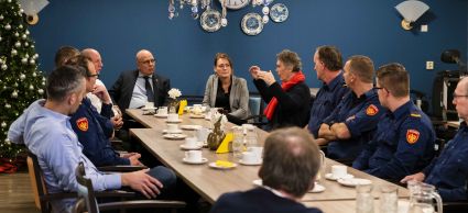 Medewerkers van de brandweer, gemeente en zorginstelling en inwoners zitten aan een tafel te praten