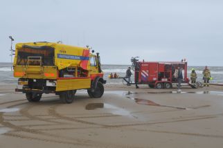 Foto van een wagen van de kusthulverlening en een wagen van de brandweer op het strand 