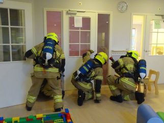 Foto van drie brandweermensen tijdens een oefening in een kinderdagverblijf