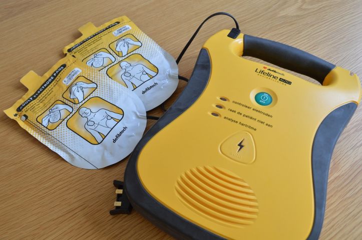 Foto van een AED liggend op een houten tafel